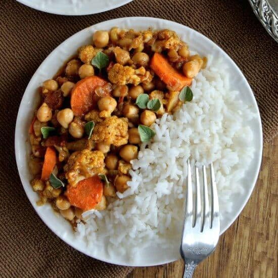 Overhead view divided in half with white rice on one side with rice orange Vegetable curry colors of mixed veggies.