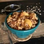 Slow Cooker Apple Oatmeal is mounded in a turquoise bowl with golden apples peeking out.