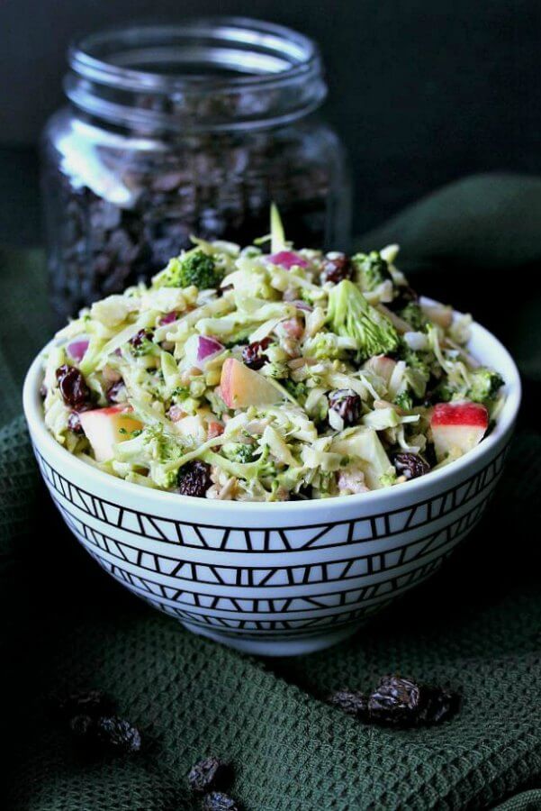 Vegan Apple Broccoli Salad is vividly colored in a zigzag patterned black and white bowl. Finely chopped vegetables and fruit fill the bowl.