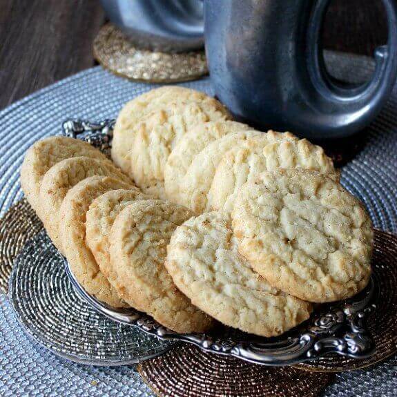 Cookies on a silver tray and sitting golden on top of copper, brass and silver rounds.