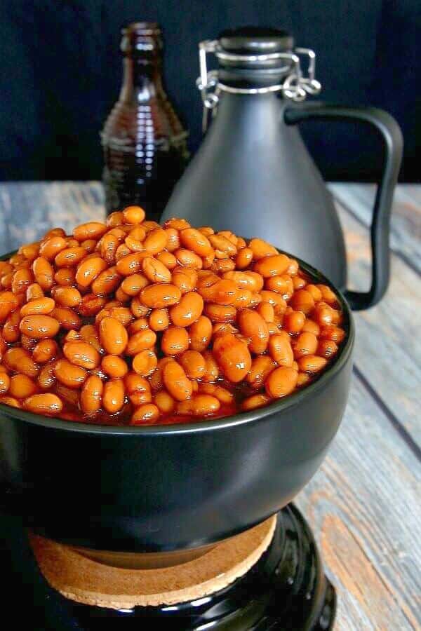 BBQ Baked Beans in their rust red color and piled high in a black bowl.