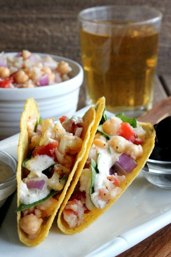 Ranch Cauliflower Tacos are angled toward the camera so there's a great view of corn tortillas filled with chunks of veggies and ladled with homemade vegan ranch dressing.