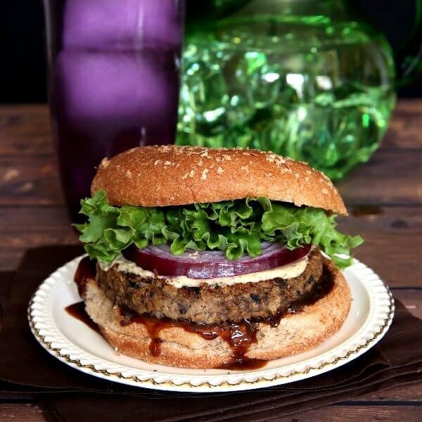Vegan Mushroom Pecan Burgers are are oozing with hoison sauce with bright layers of curly lettuce and red onion.