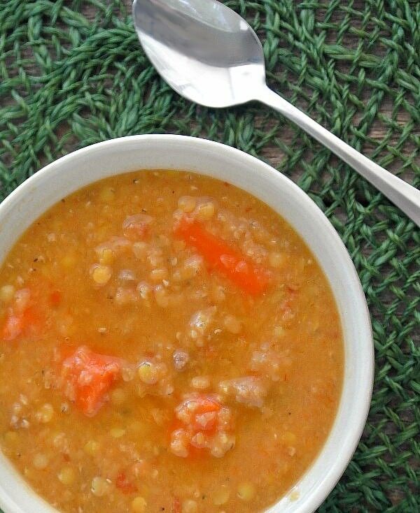 Slow Cooker Red Lentil Soup is an overhead closeup of rich orange lentil soup with pieces of carrot peeking out.