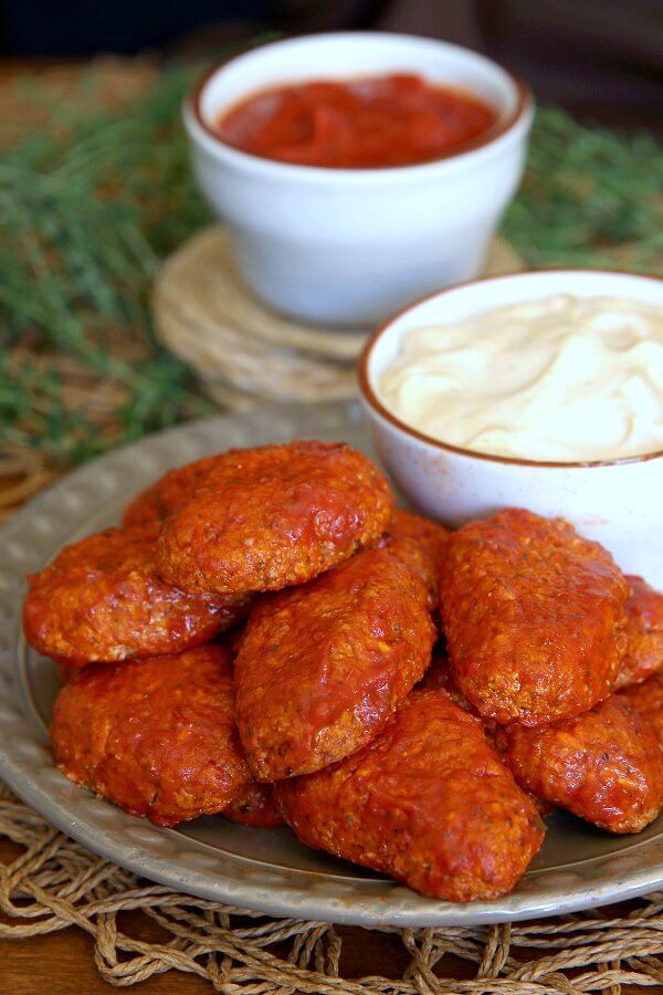 Boneless BBQ Buffalo Wings are baked in hot red and sweet sauce then piled high on a plate next to a creamy chipotle white sauce.