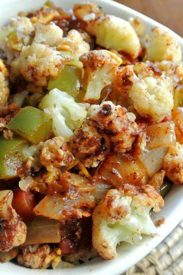 Mexican Cauliflower Casserole is piled high with a super close up photo of baked veggies covered with super inviting and colorful spices.