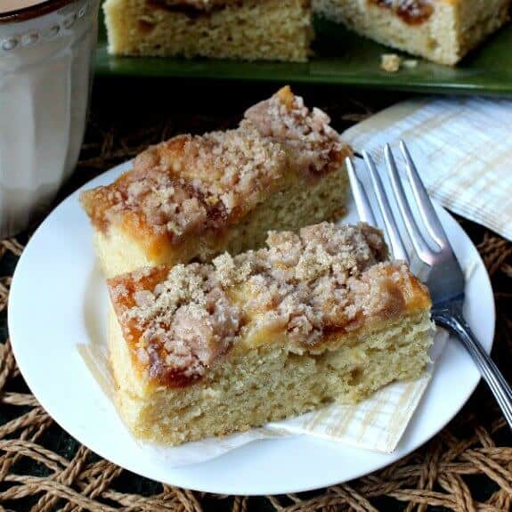 Vegan Coffee Cake with Apple Cinnamon Streusel is tilted forward with two slices sitting on a gold and white abstract patterned napkin and a white plate. A fork at the ready