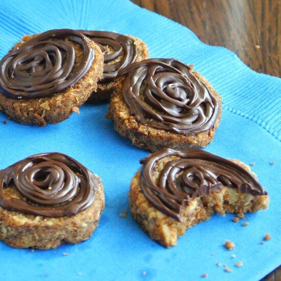 Chocolate Island Hawaiian Cookies are spread out on a turquoise napkin. A bite is taken from the front cookie with a few crumbs around.