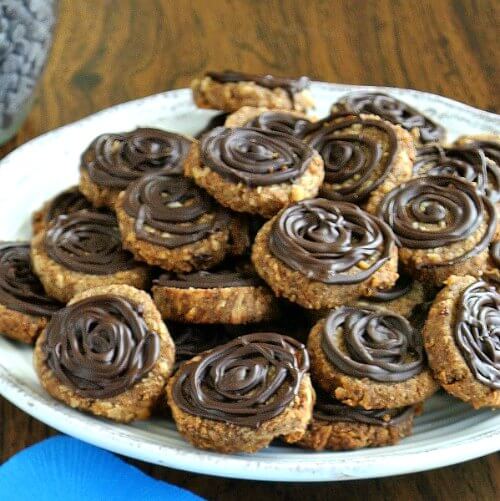 Chocolate Island Hawaiian Cookies are piled on a white plate against a turquoise napkin. Chocolate swirls the top of each cookie.