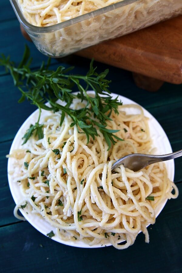 Vegan Chicken Tetrazzini Casserole is spaghetti that is covered with rich white sauce, woven with seitan and sprinkled with green tarragon. All on a white plate.