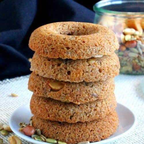 Baked Trail Mix Cake Donuts are stacked five high. Light golden brown with hints of pumpkin seeds and nuts peeking out.