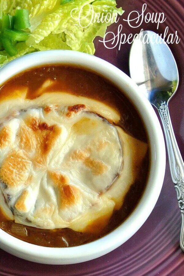 Homemade French Onion Soup with an overhead view of a rich brown onion soup topped with a slice of French bread and melted vegan cheese. In a white bowl against a deep purple background.
