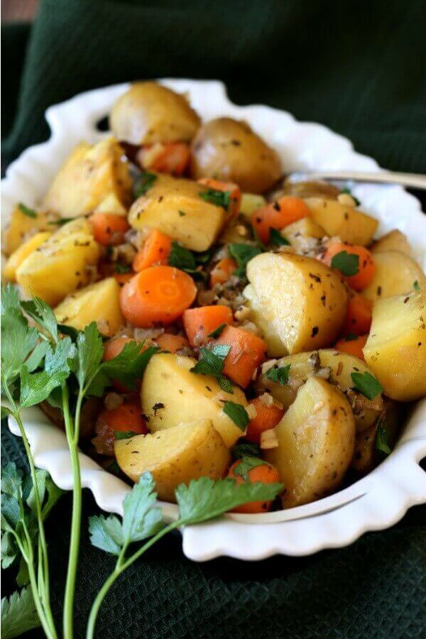 Instant Pot Potato Carrot Medley if filling a white milk glass scalloped bowl with fresh parsley sprinkled over the top.