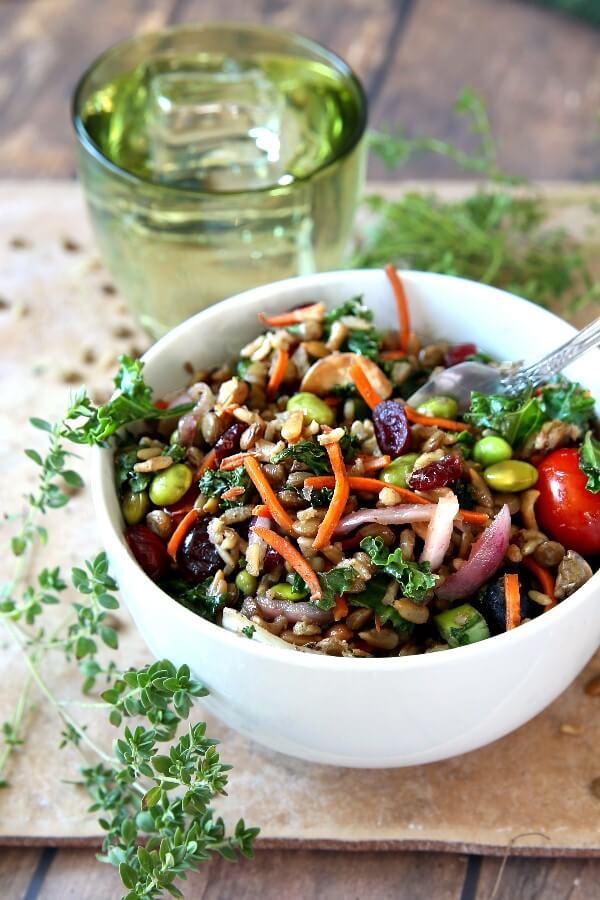 Superfood Salad with Maple Vinaigrette has every color of the rainbow in deep rich shades. It's all in a white bowl with fresh herbs in front on the granite slab.