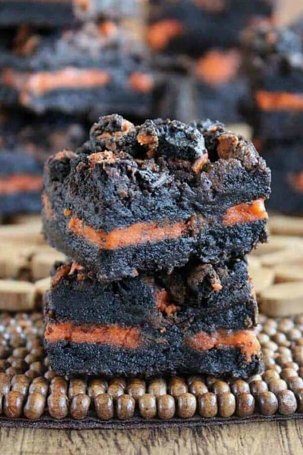 Autumn Oreo Brownies are cut int a square and the is a layer of orange oreo cookies center going through the middle of the brownie.