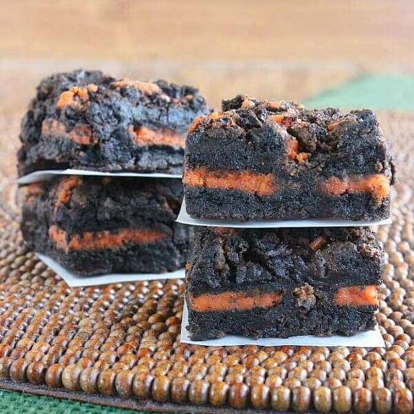 This oreo brownie recipe is cut into squares and the oreo layer is orange.