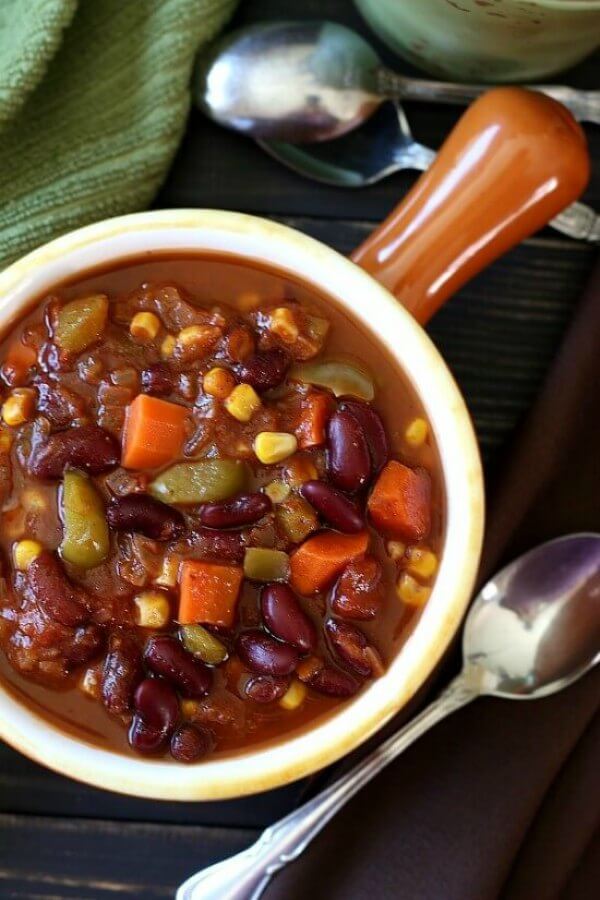Caribbean Chili is features as an overhead photo with the lovely colors of kidney beans, carrots, corn and green bell pepper. It's all being served in an orange handled bowl.