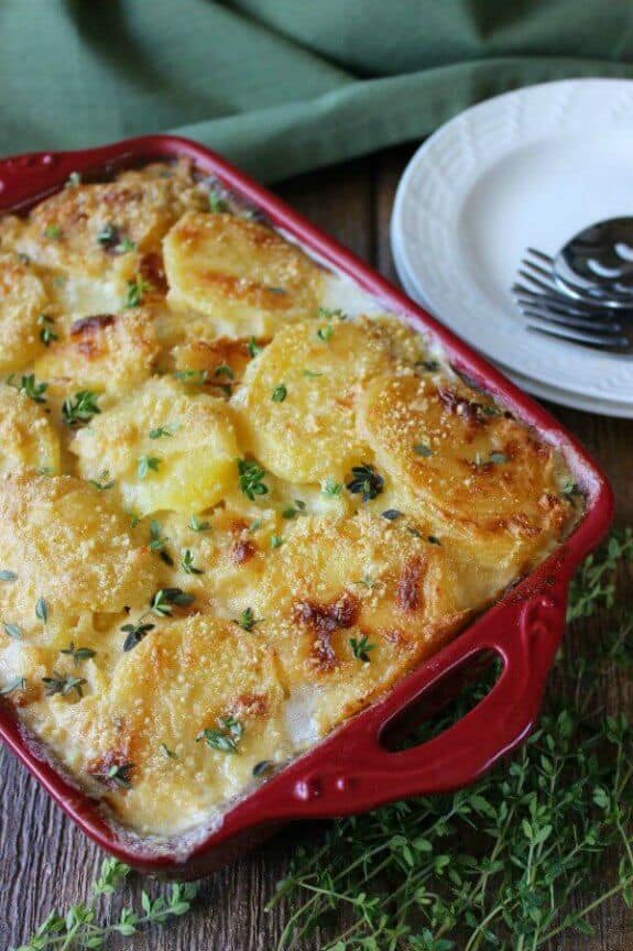 Dairy Free Herbed Scalloped Potatoes is tilted towards you in a red casserole dish.