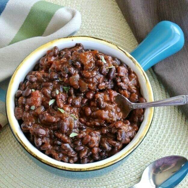 Slow Cooker Black Bean Chili is featured as an overhead photo with the lovely colors of a rich chili. It's all being served in an turquoise handled with a colorful striped cloth on the side.