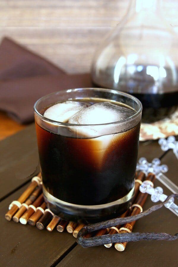 Homemade Kahlua is poured into a glass and has two giant ice cubes. 
