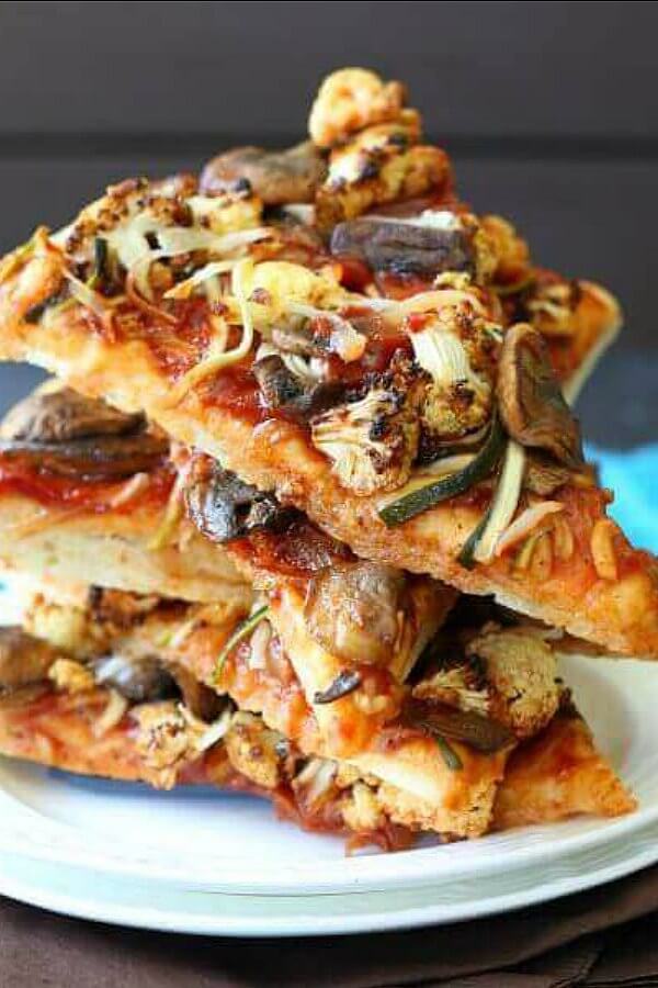 Vegan BBQ Veggie Pizza is stacked five slices high at all angles with glistening veggies showing throughout.