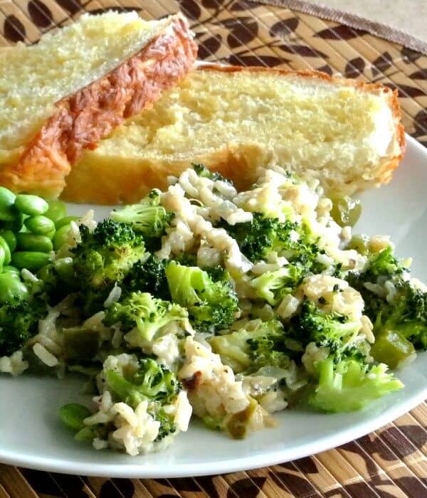 Vegan Broccoli Rice Casserole is a photo at an angle of the broccoli mix on a white plate with toasted Italian slices sharing the white plate.