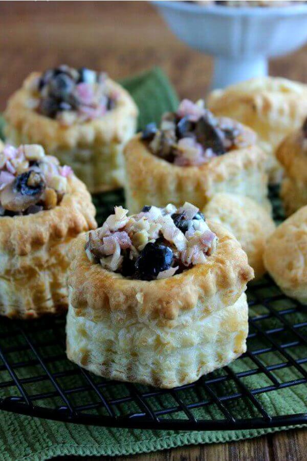 Vegan Puff Pastry Appetizer is photographed with filled pastried lined up on a black cooling rack. They are sitting on a green mat.