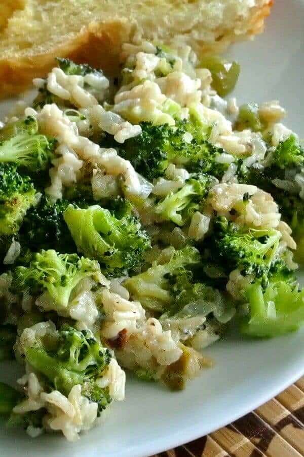 Vegan Broccoli Rice Casserole is a close-up picture with broccoli, rice and dairy-free cheese on a white plate and a bamboo painted mat.