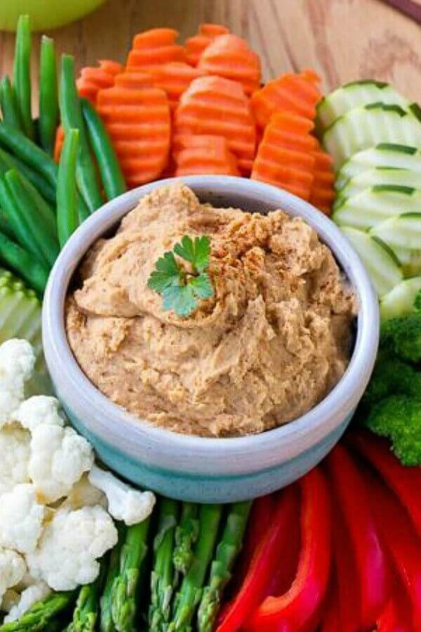 White Bean Dip is in a small bowl and surrounded with piles of colorful fresh sliced veggies.