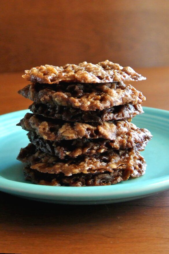 Chocolate Oatmeal Lace Cookies are stacked perfectly straight and seven cookies high on a turquoise plate. Lacey edges abound.
