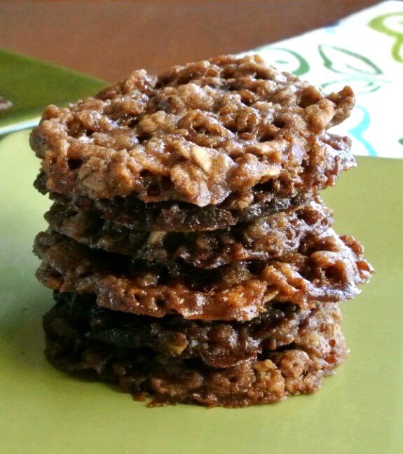 Chocolate Oatmeal Lace Cookies are stacked six cookies high in a green square plate. A white, green and turquoise cloth lays behind.