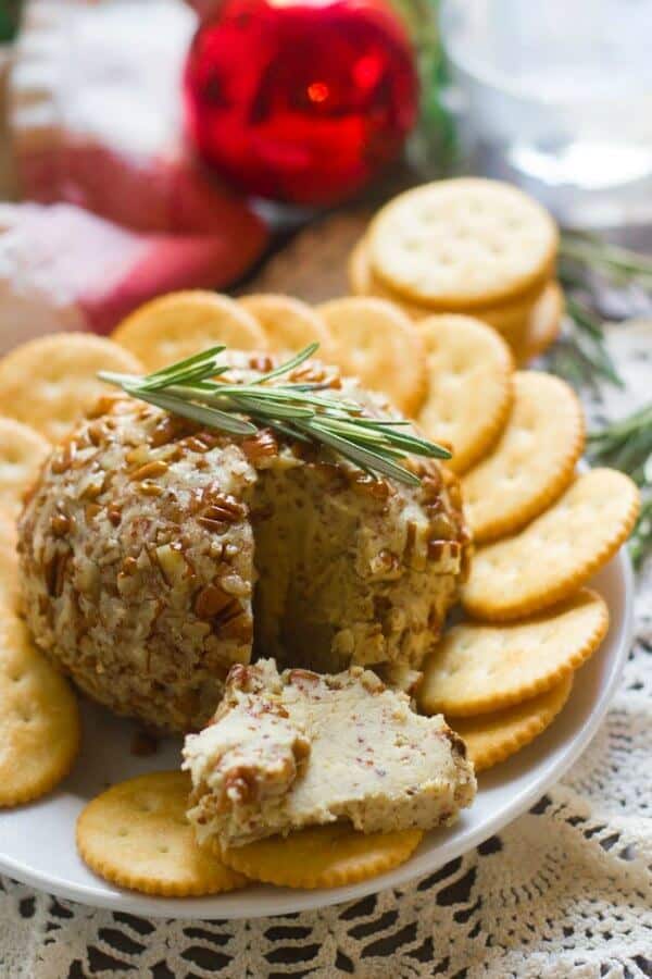 Maple Dijon Vegan Cheese Ball is sliced and bring spread on a cracker. Included in the list of 17 Vegan Party Appetizers.