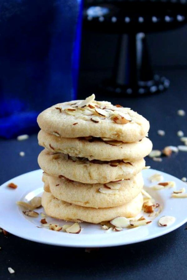 Chinese Almond Butter Cookies are sitting on a white plate against shades of navy blue and black.