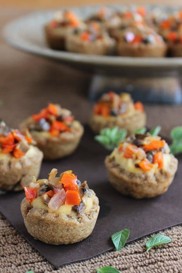 Garlic Hummus Stuffed Mini Bread Bowl Appetizers are lined up on a chocolate colored napkin with sauted veggies piled high.