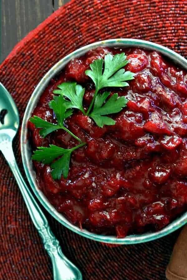 Homemade cranberry sauce fills a bowl on a red beaded mat.