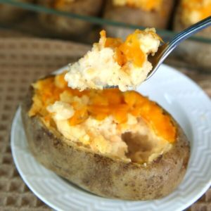 Dairy-Free twice baked potatoes are in a casserole with one on a front plate. A forkful is right in front.