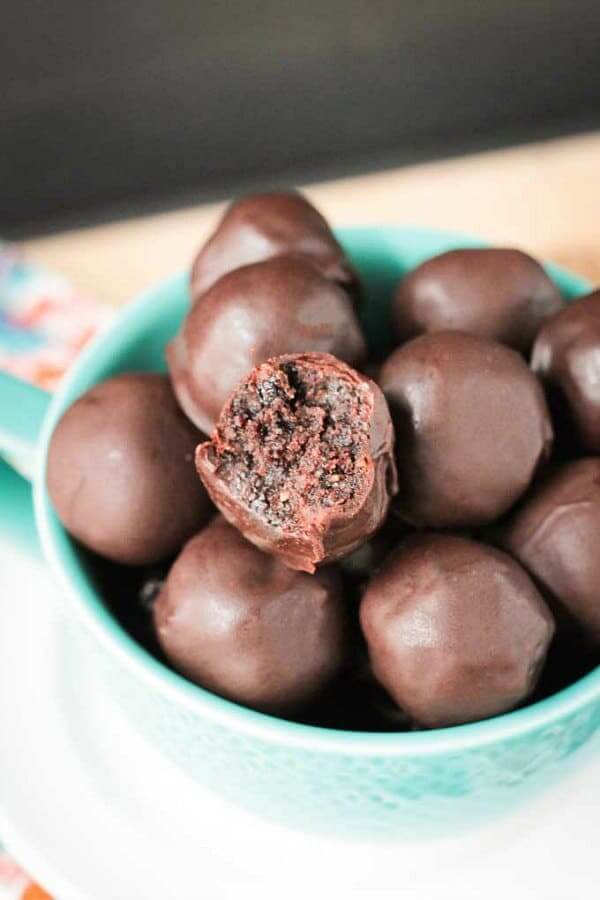 Cherry Chocolate Walnut Truffles are piled high in a turquoise bowl with a bite out of the top one.