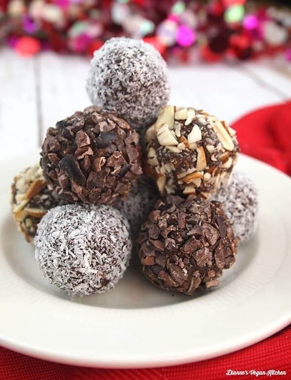 Vegan Chocolate-Almond Date Truffles stacked in a pyramid on a red cloth and white plate.