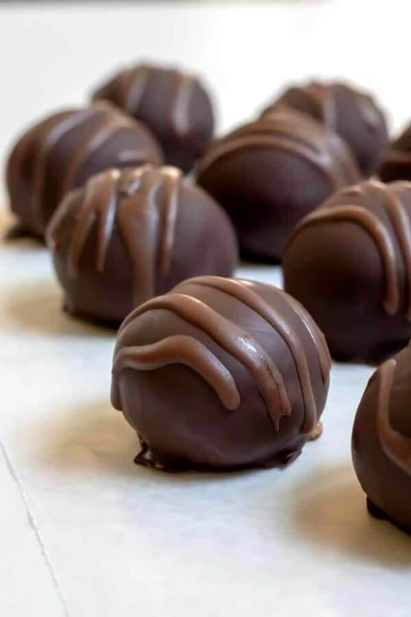 Peanut Butter Chocolate Chip Cookie Dough Truffles are photographed straight on with a contrasting chocolate drizzled across top.