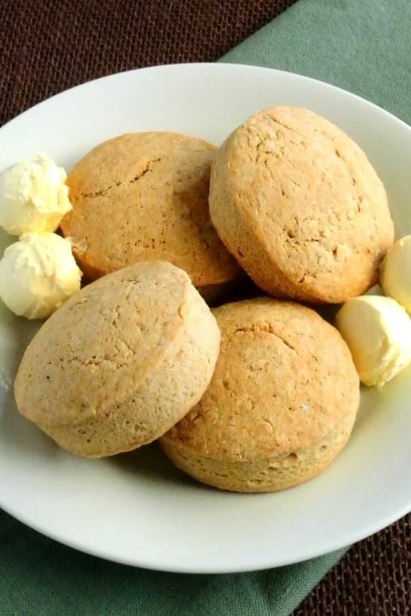Four big fat Irish Scones are sitting on a plate with four scoops of dairy-free butter.