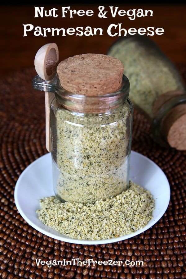 Nut Free Vegan Parmesan Cheese is in a cork topped jar with some spilled on the plate it's sitting on.