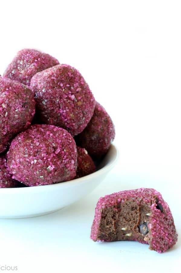 A bowlful of pink covered vegan chocolate protein bites with one bite out of the one in front.