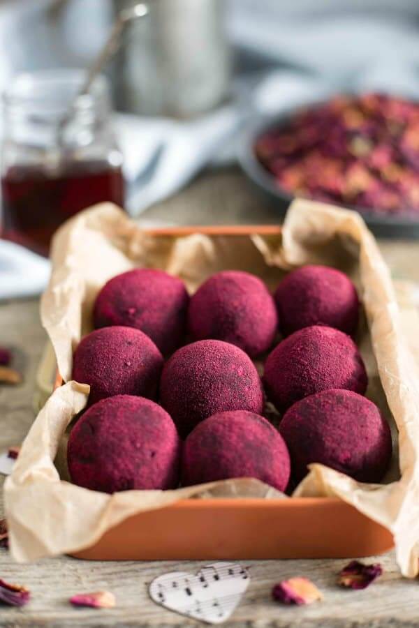 Beet powder covered chocolate peanut butter truffles are lined up 3x3 in a parchment lined box.
