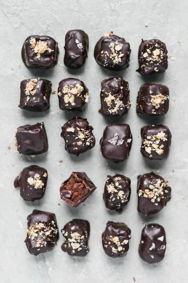 Twenty lovely Vegan Chocolate Hazelnut Truffles are lined up 4x5 and sprinkled with assorted toppings.