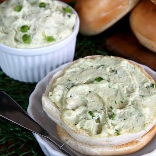 Dairy Free Cream Cheese is spread on a toasted bagel half with chives peeking through.