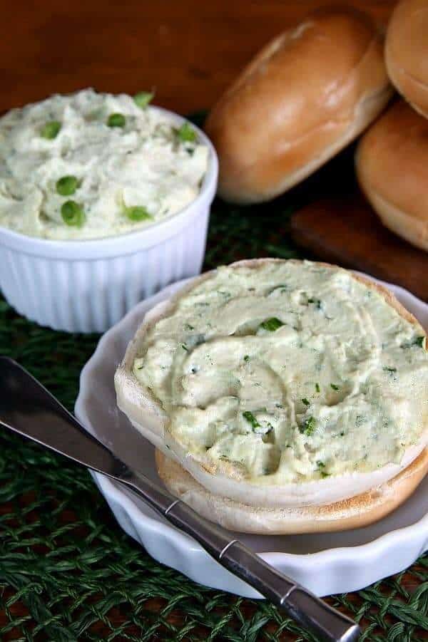 Dairy Free Cream Cheese is spread on a toasted bagel half with chives peeking through.