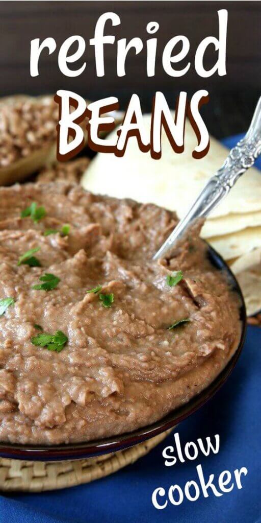 Serving bowl filled with refried beans with a large spoon scooped in the bow. with tortillas behind.