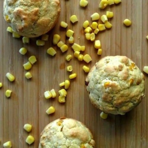 Vegan Cornbread Muffins photographed from overhead on a wooden cutting board with corn sprinkled around.