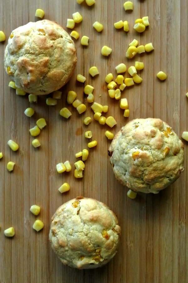 Vegan Cornbread Muffins photographed from overhead on a wooden cutting board with corn sprinkled around.