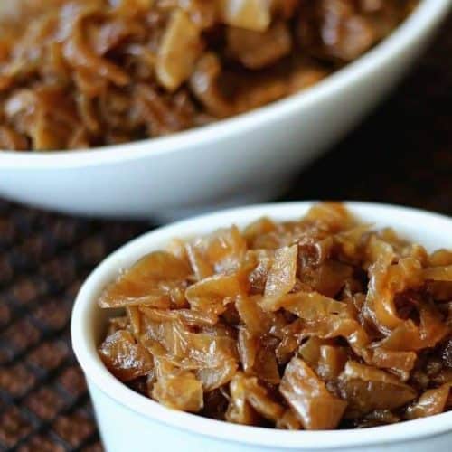 Close up photo of two white bowls filled with glistening golden slow cooker caramelized onions.
